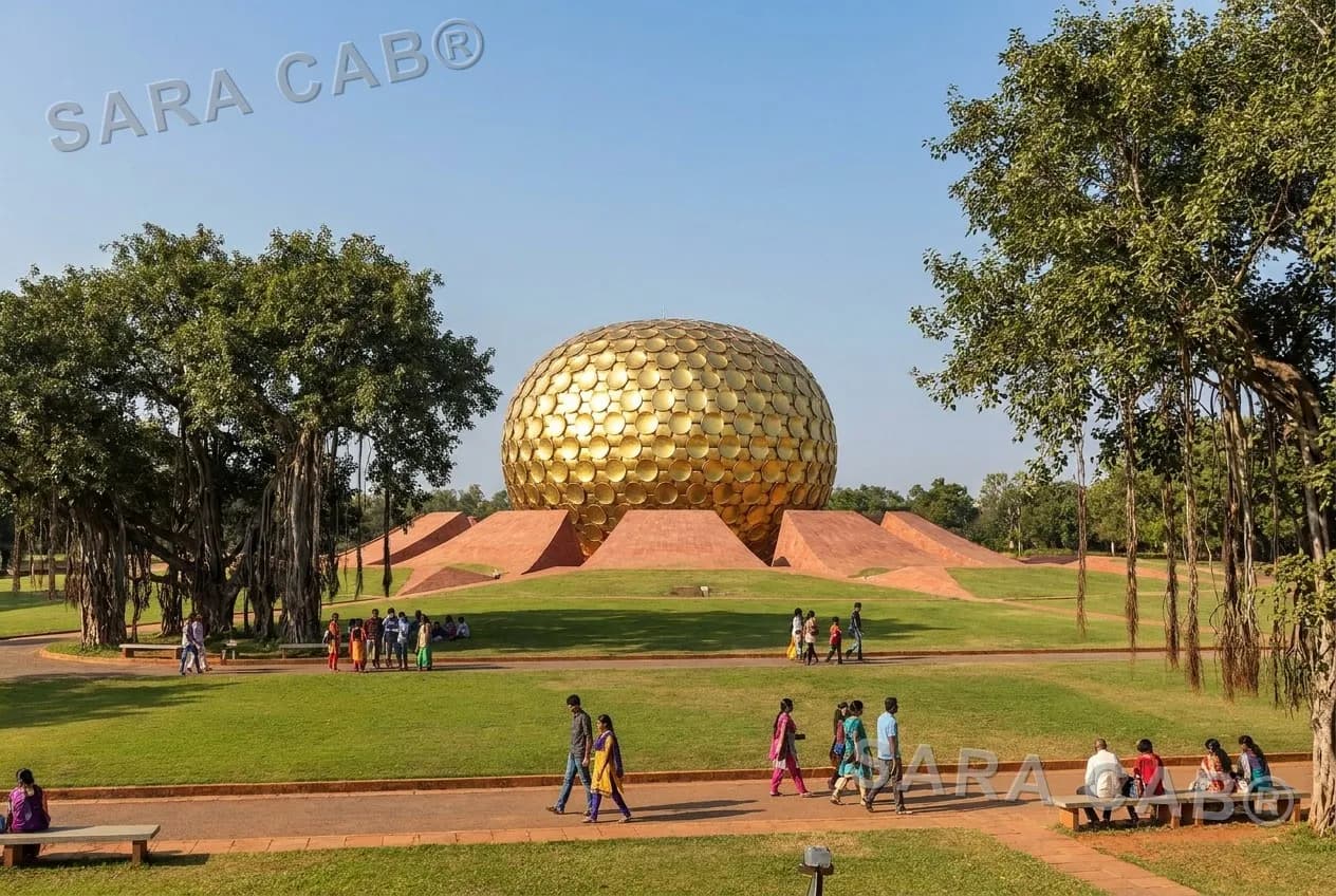The golden Matrimandir in Auroville seen across lawns and banyan trees from the public viewing point